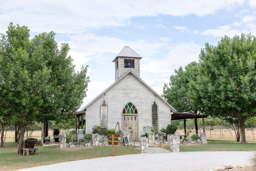 Gruene Estate wedding venue in the historic Gruene District of New Braunfels, Texas featuring a charming open-air chapel surrounded by oak trees.